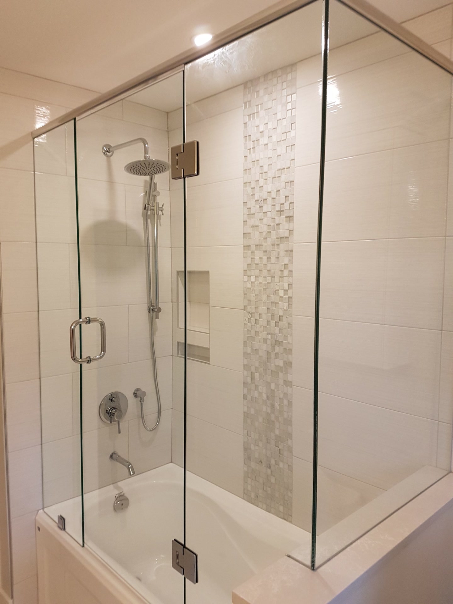 Bathroom shower with frameless glass, a rain shower head and a mosaic feature strip