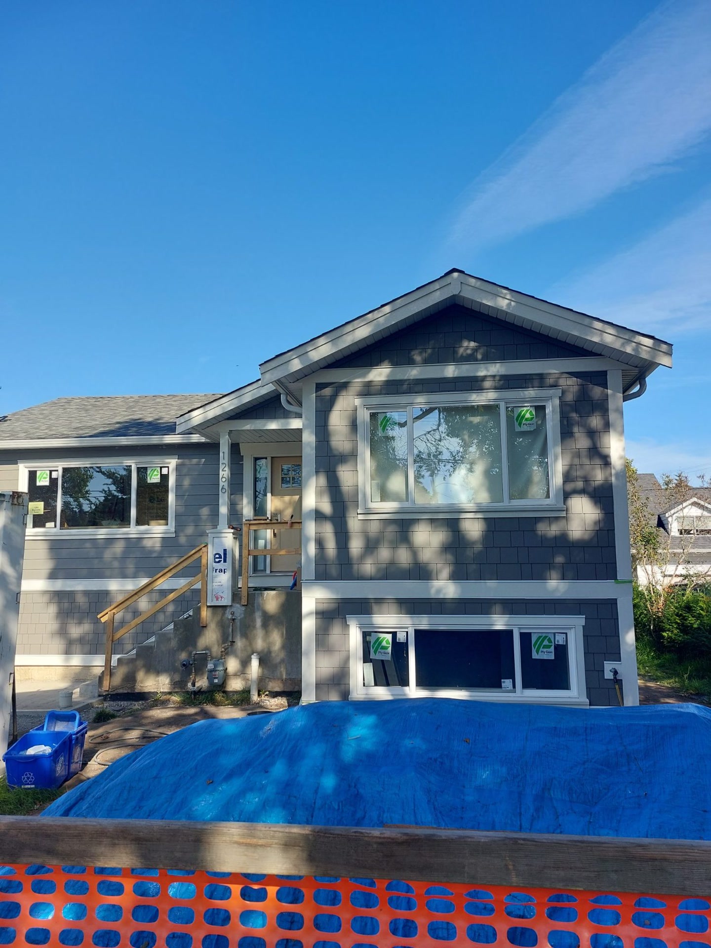 Front of a house mid-renovation with new grey shingle and lap siding and white trim