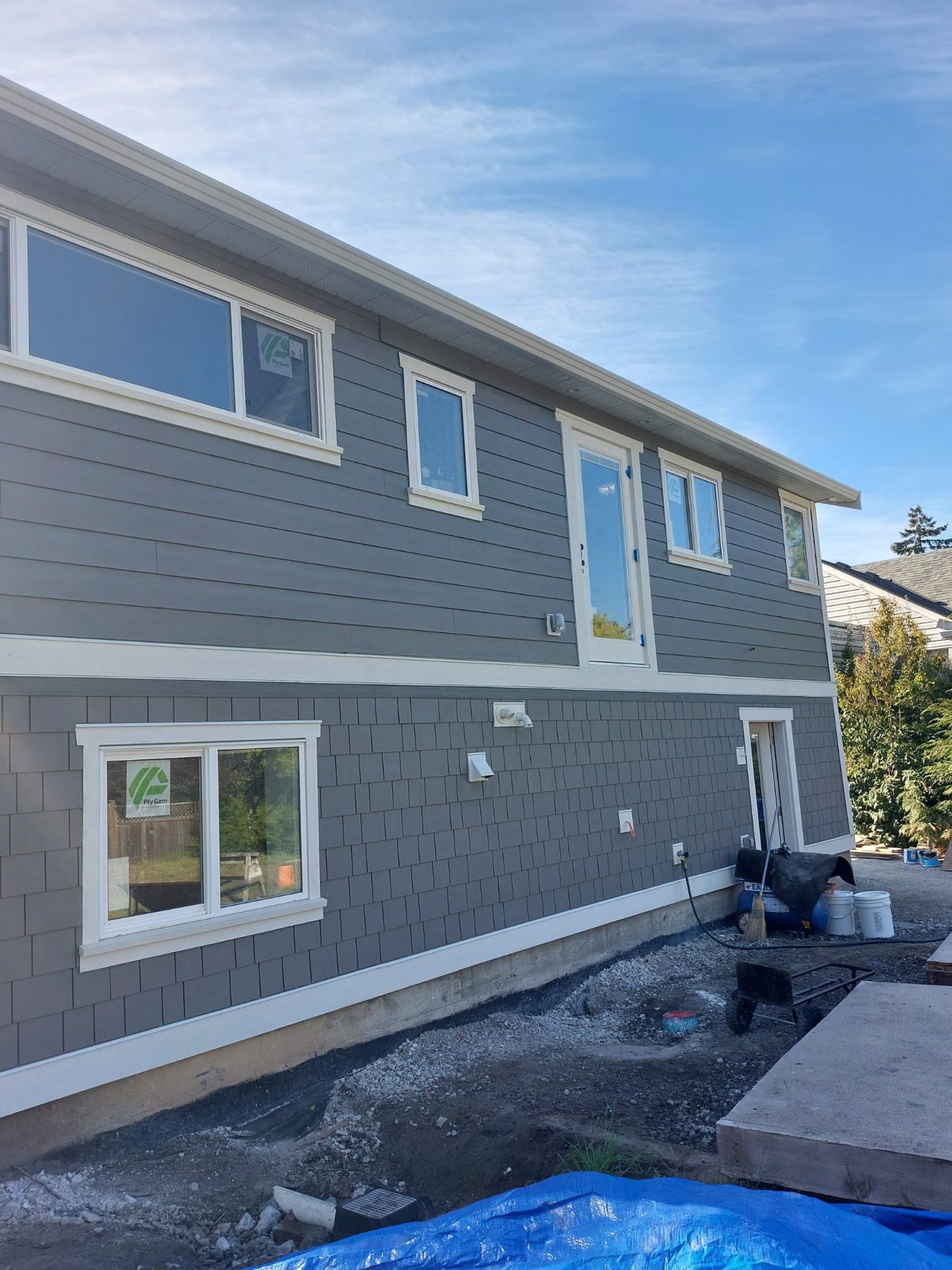 Side of the same house mid-renovation, grey siding wrapped and trimmed