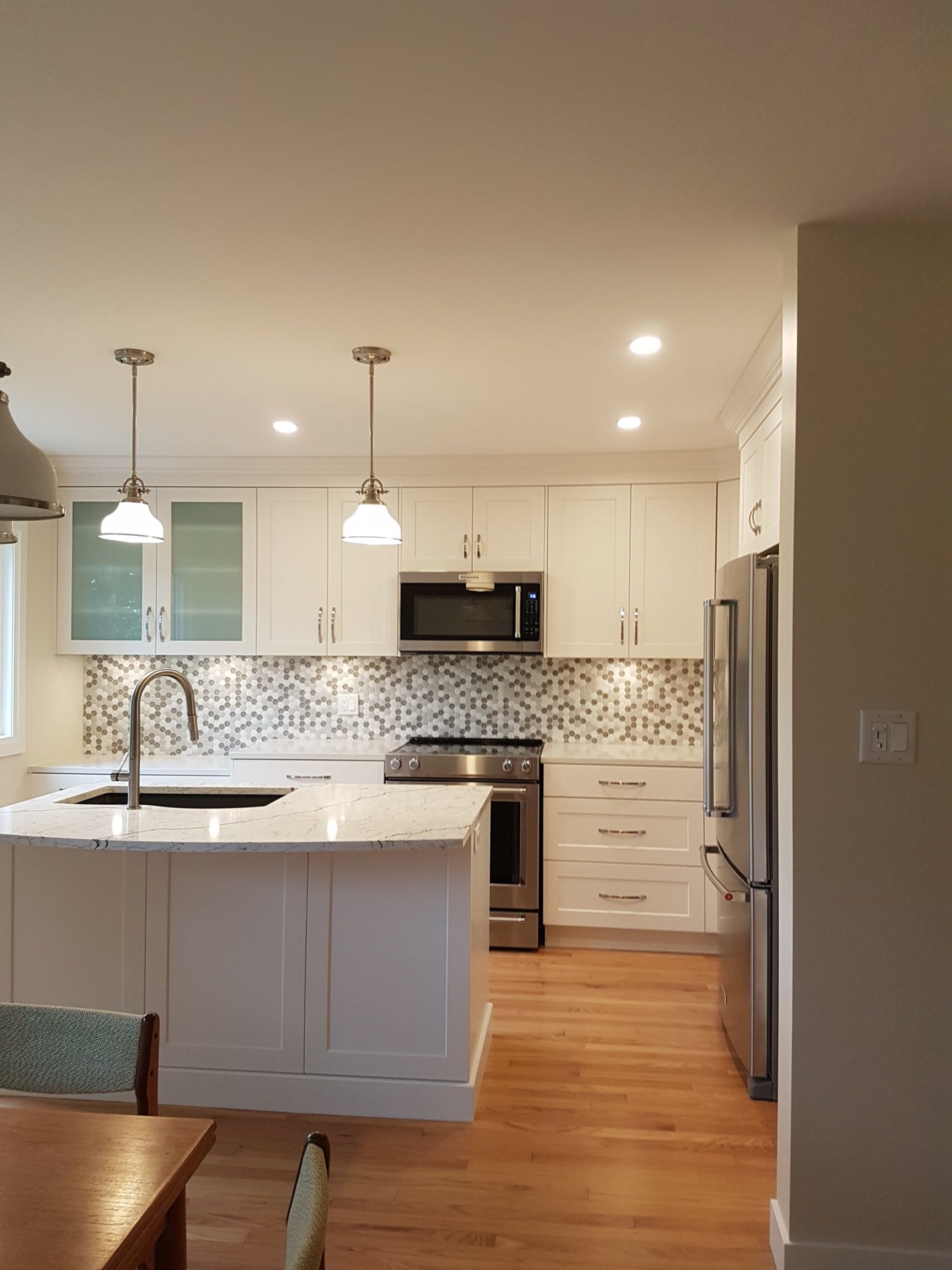 Finished kitchen with white shaker cabinets, a quartz island and a hexagon mosaic backsplash